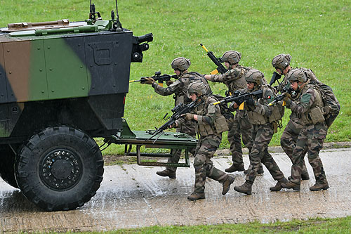 Les soldats progressent à l'abri du véhicule blindé