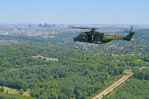 Hélicoptère NH90 Caïman au-dessus du Parc Royal de Marly-le-Roi. Au centre l'Aqueduc de Louveciennes. Au loinla Défense et la Tour Eiffel