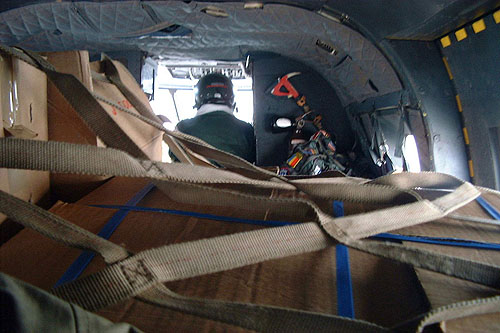 Vue sur le chargement dans la soute de l'hélicoptère Puma. De dos, le mécanicien naviguant