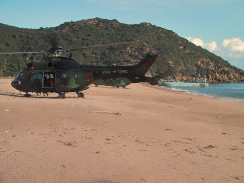 Hélicoptères Cougar sur la plage, au fond, un chaland de débarquement vient d'accoster