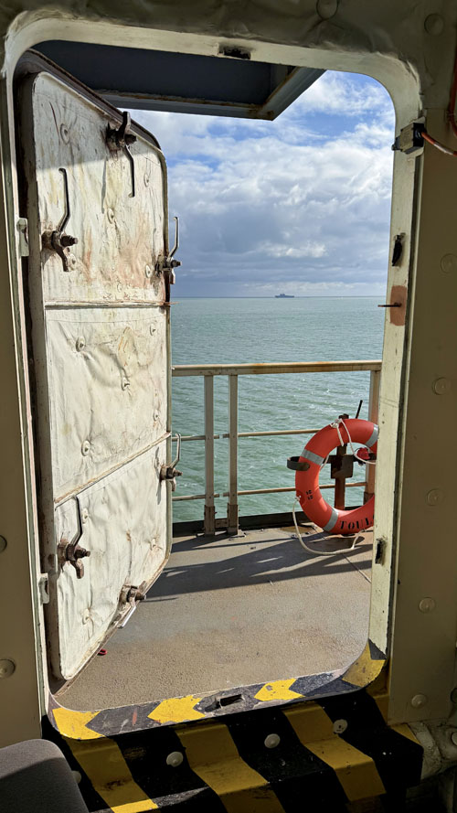 Après plusieurs ponts sans lumière naturelle, une porte s’ouvre enfin sur l’extérieur et laisse apparaître la mer
