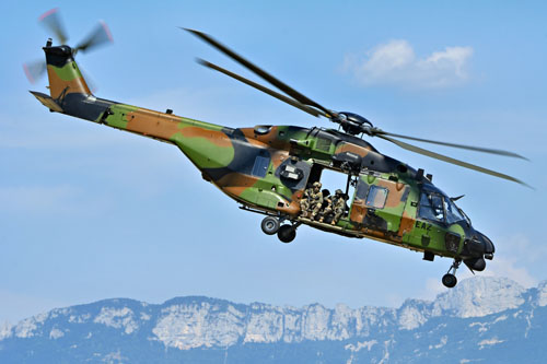 Assis à la porte du NH90 Caïman, des commandos assurent la protection de l'hélicoptère, prêts à riposter en cas de tirs ennemis