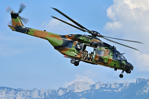 Assis à la porte du NH90 Caïman, des commandos assurent la protection de l'hélicoptère, prêts à riposter en cas de tirs ennemis