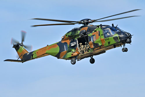Assis à la porte du NH90 Caïman, des commandos assurent la protection de l'hélicoptère, prêts à riposter en cas de tirs ennemis