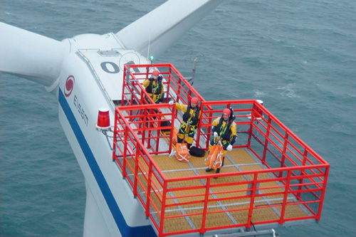 Un hélicoptère hélitreuille des techniciens de maintenance sur une éolienne